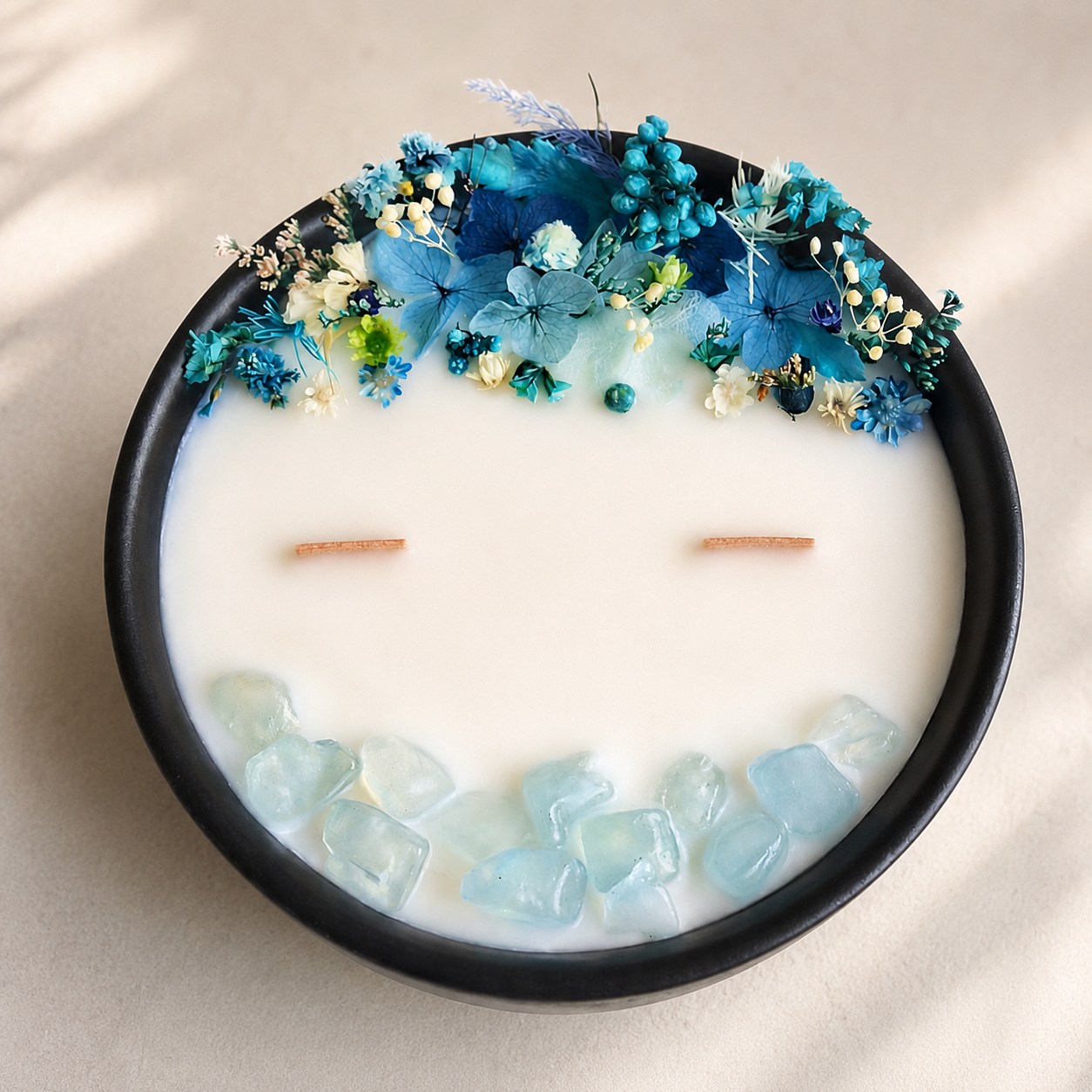 Close-up of Blue Bloom and Aquamarine floral crystal candle with preserved blue flowers, aquamarine stones and two wooden wicks