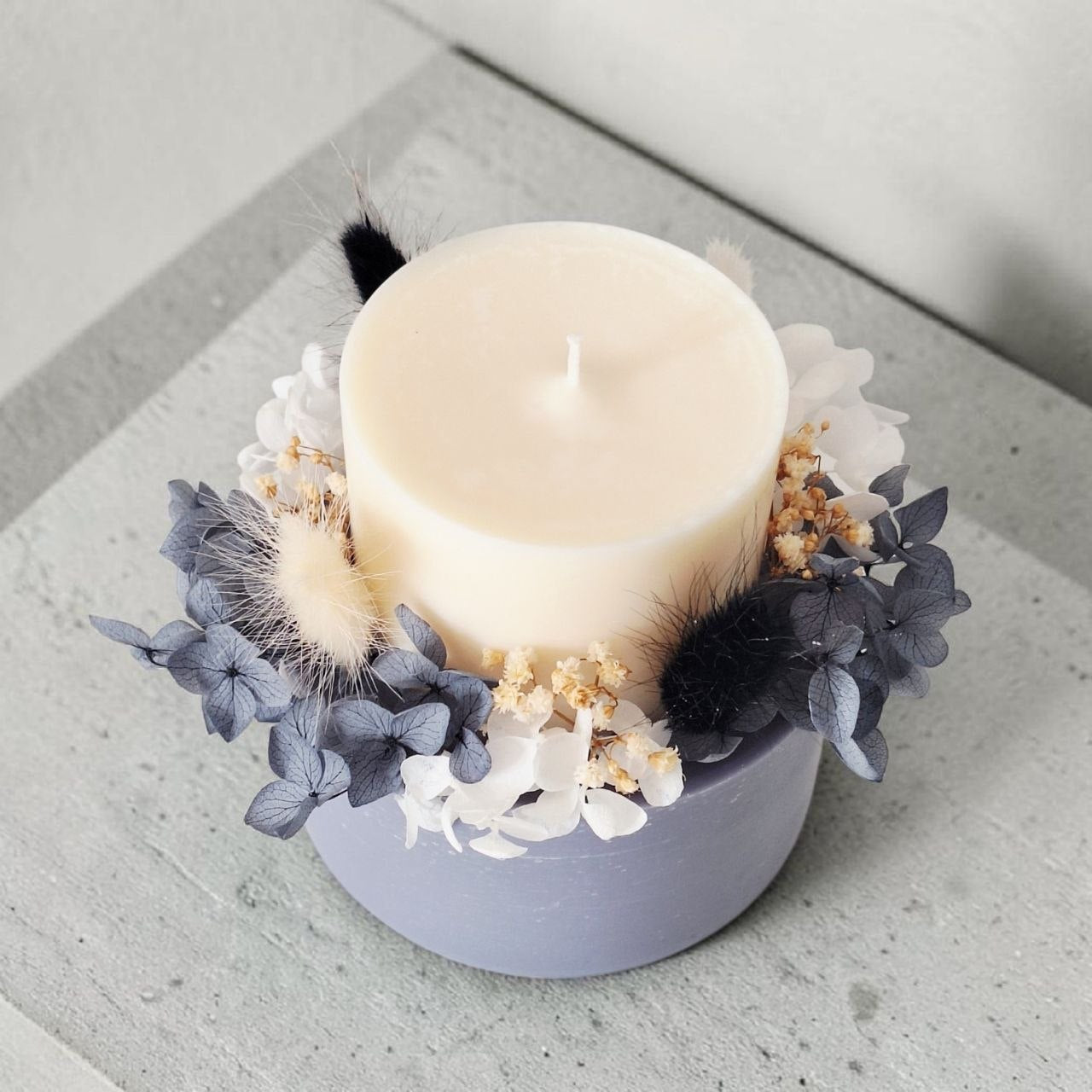 Top view of midnight grey botanical candle with preserved flowers arranged around the candle