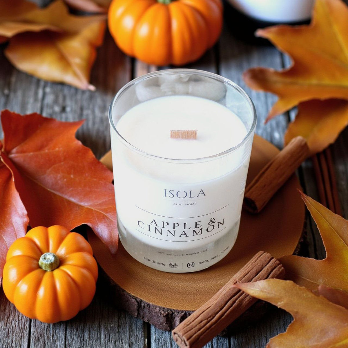 Apple and cinnamon scented candle styled with autumn leaves, cinnamon sticks and decorative pumpkins