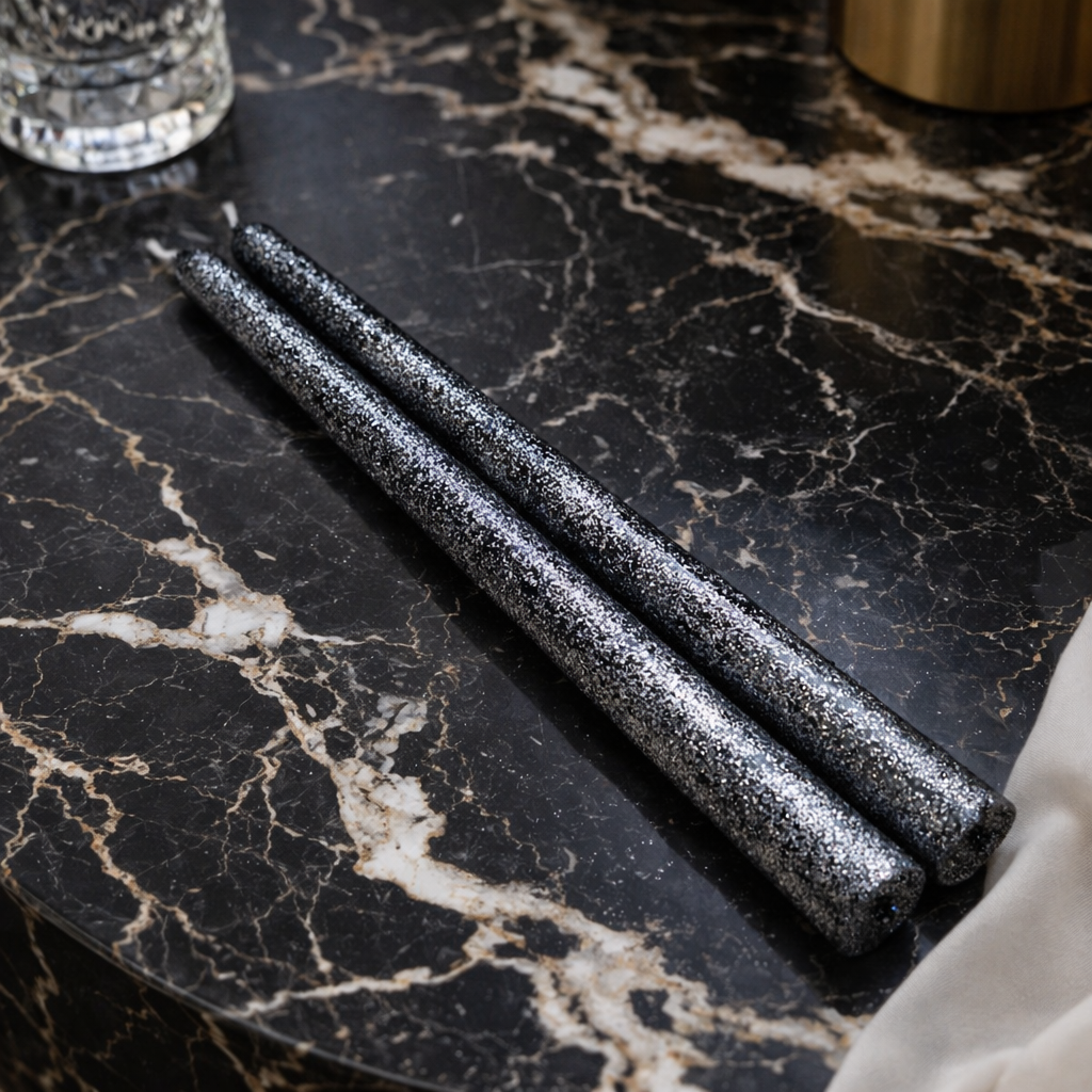 Close-up of handmade black taper candles with textured silver decorative finish