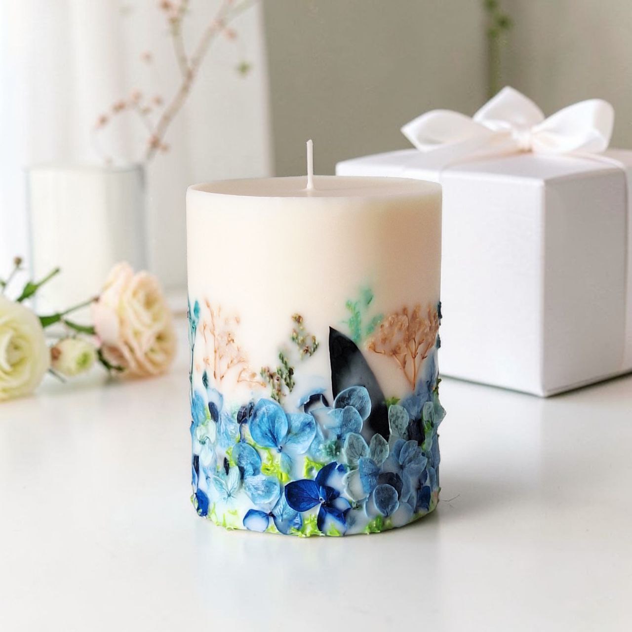 Blue botanical soy wax candle with white gift box and ribbon, ready to gift