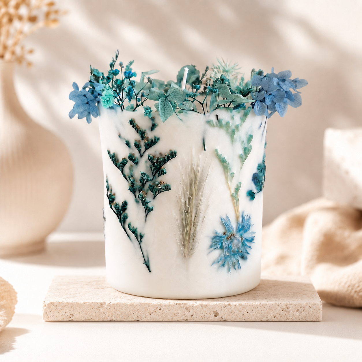 Blue botanical soy wax candle with dried flowers in a light neutral interior, handmade in Belgium
