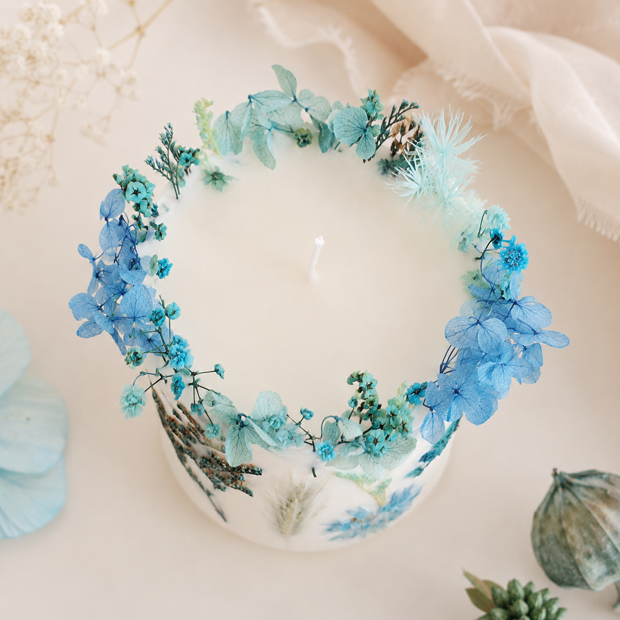 Top view of blue botanical soy wax candle decorated with real dried flowers