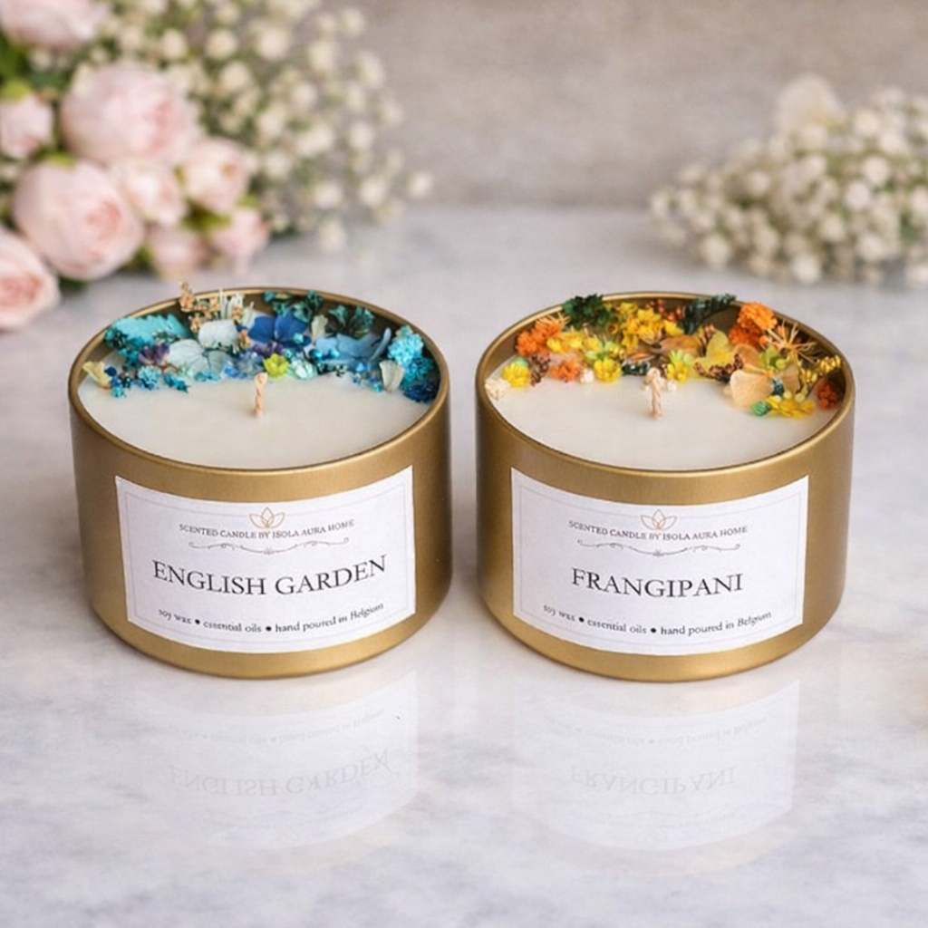 Two designer floral soy wax candles in gold tins with blue and yellow botanical decoration, handmade by Isola Aura Home in Belgium