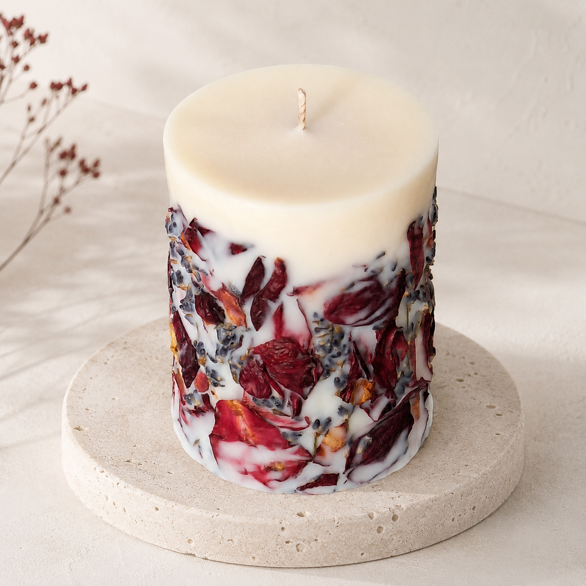 Elevated view of the floral pillar candle showing its smooth ivory wax top, centered cotton wick and dried botanical decoration around the sides.