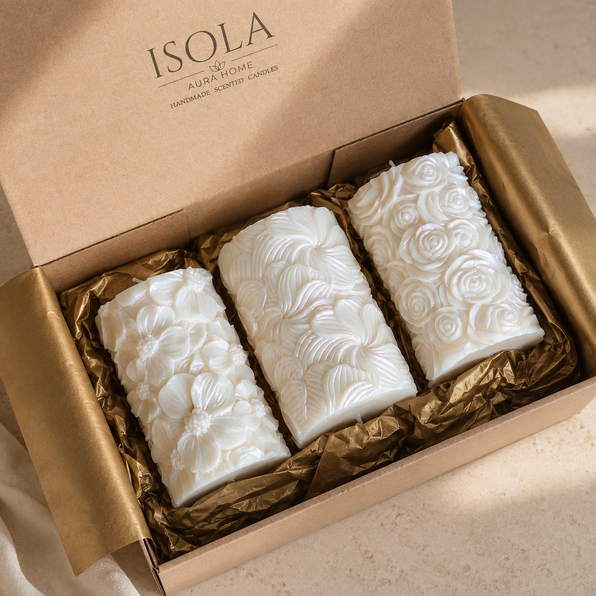 Decorative sculptural candle set displayed in an open kraft gift box with gold packaging and raised flower designs.
