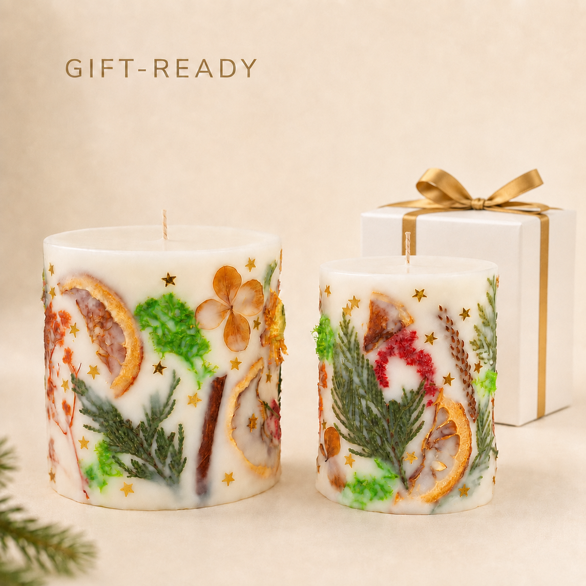 Two gift-ready botanical Christmas candles with a white gift box and gold ribbon.