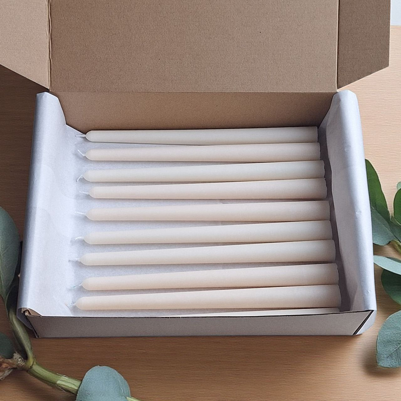 Bulk ivory taper candles carefully packed in protective paper inside a sturdy box