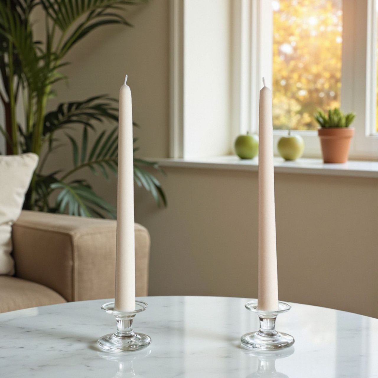 Two ivory taper candles in clear holders styled in a minimalist neutral interior