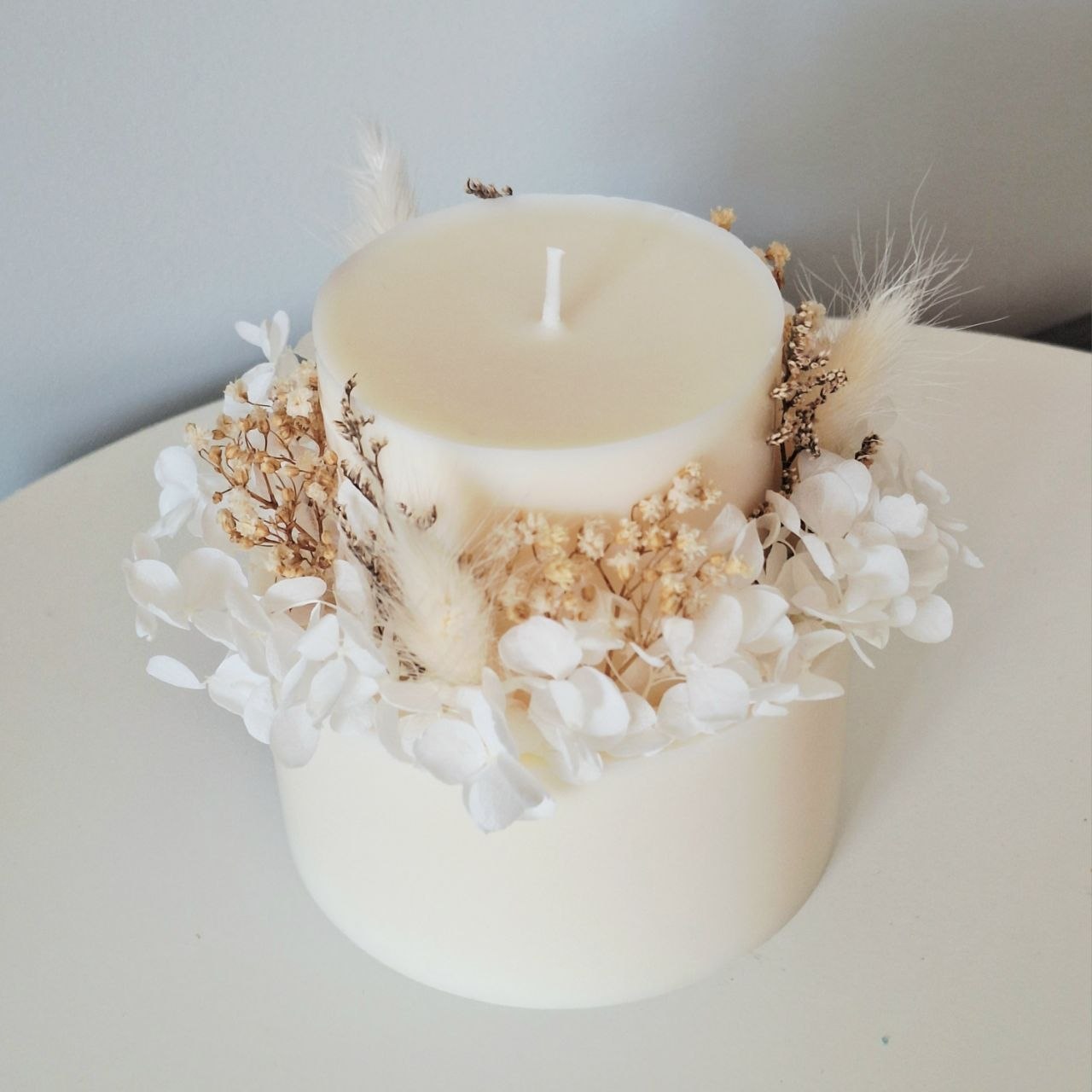 Top view of ivory white botanical candle with preserved flowers arranged around the candle