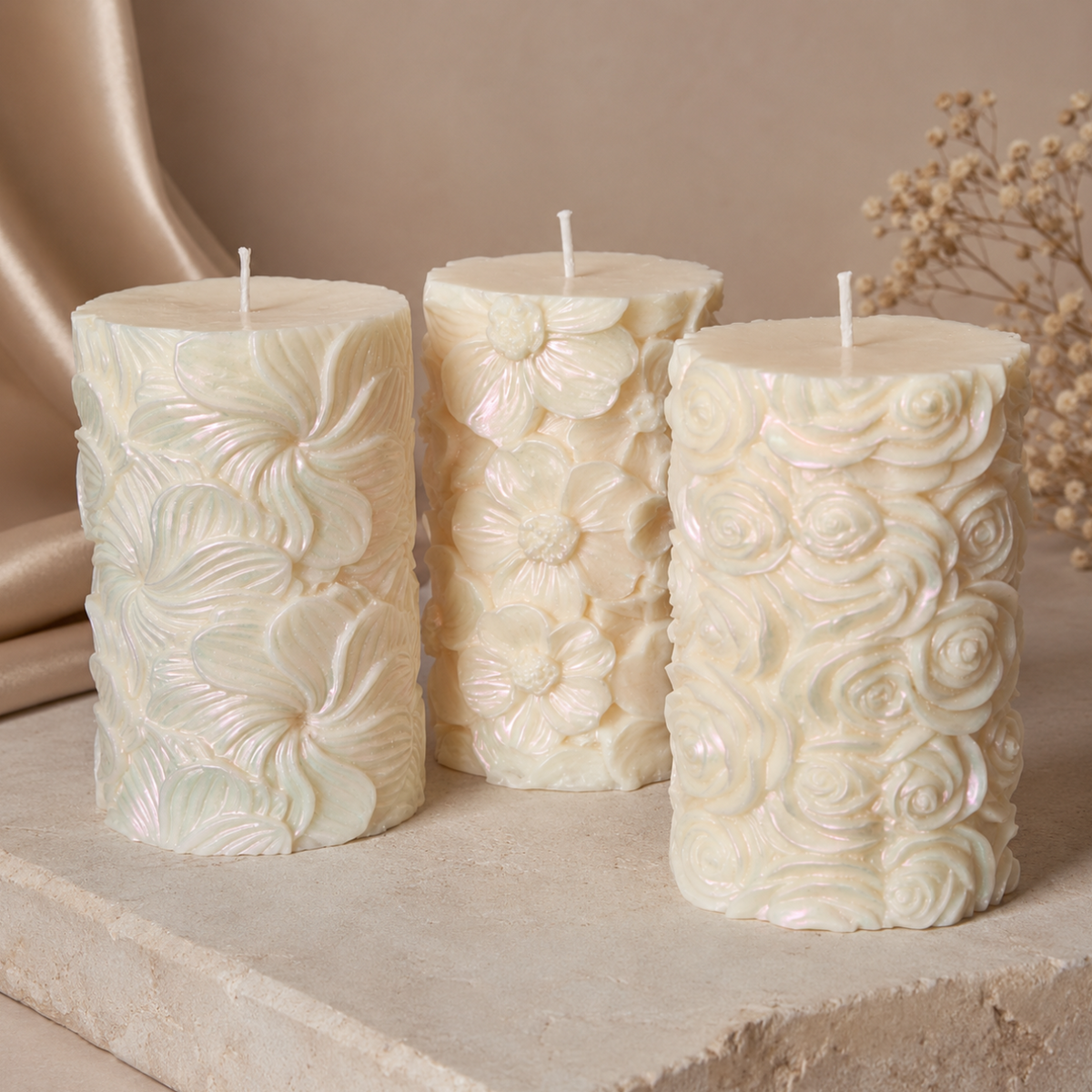 Pearlescent sculptural soy pillar candle with raised floral patterns displayed on a warm stone pedestal.