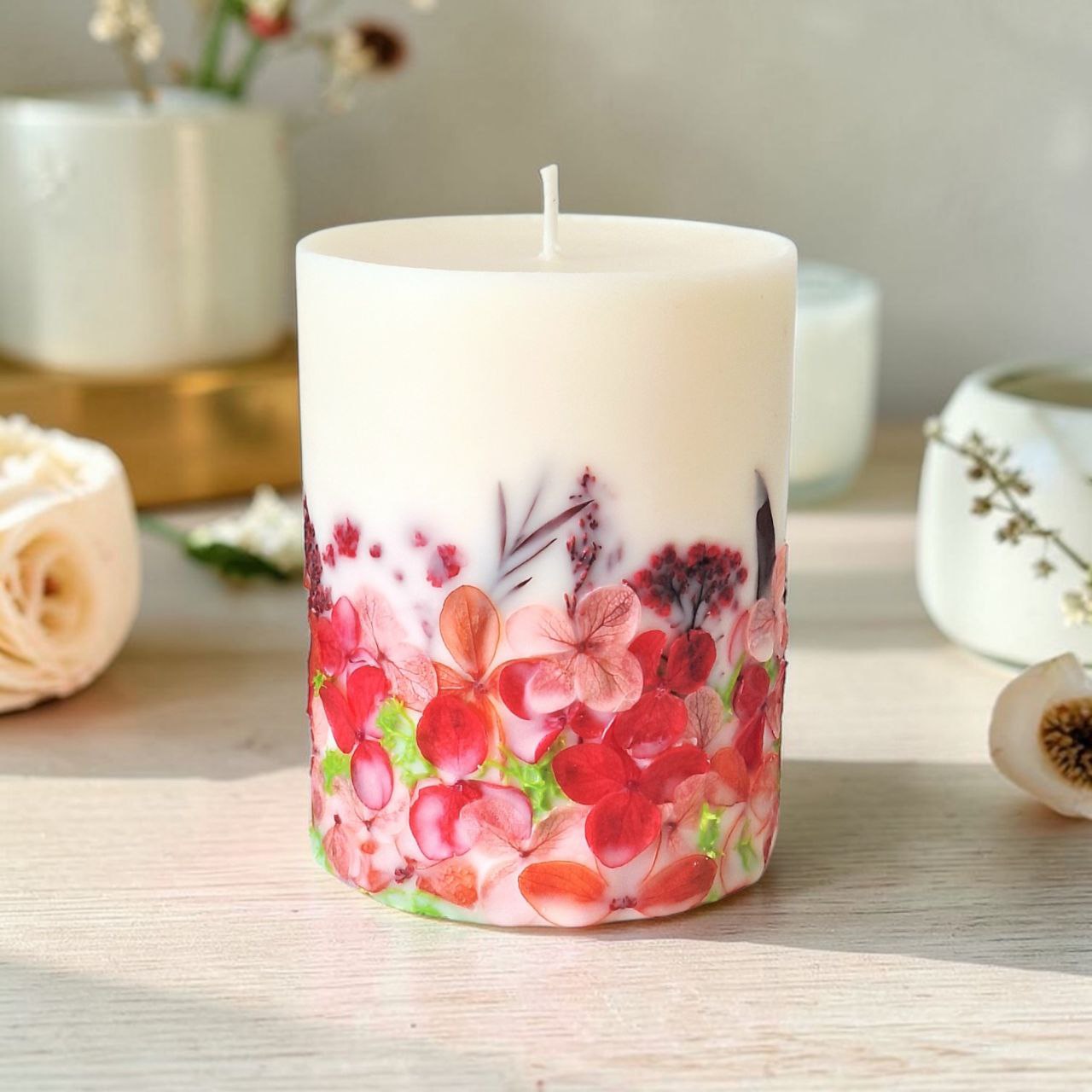 Handmade red floral candle with dried flowers in pink and red tones