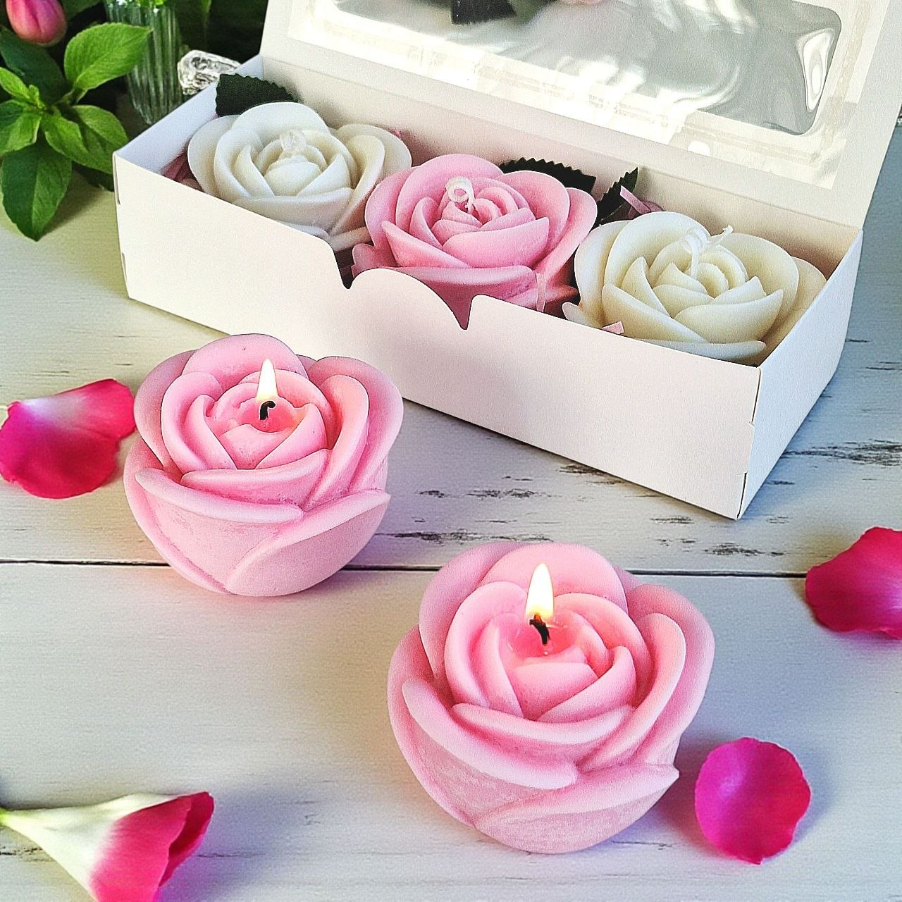 Pink rose-shaped soy wax candles burning beside a rose candle gift box