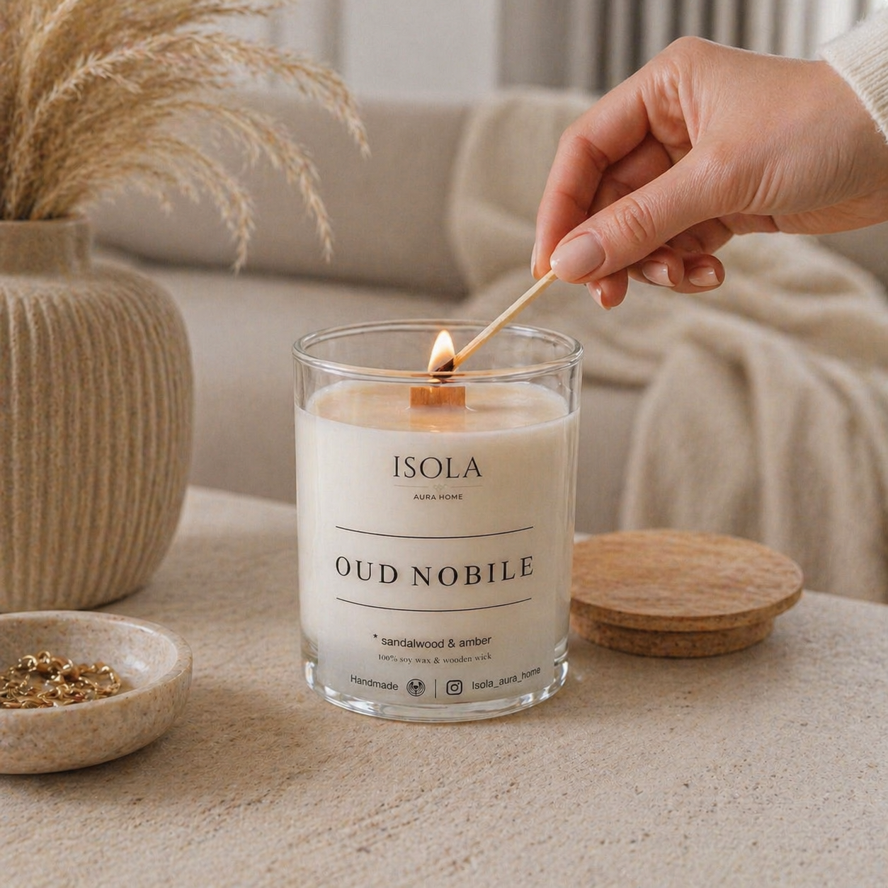 Sandalwood and Amber soy wax candle in a glass jar being lit, handmade by Isola Aura Home in Belgium