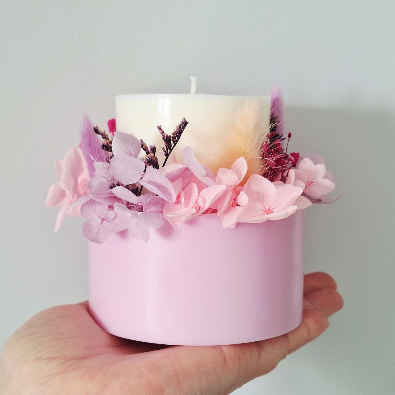 Soft rose botanical candle shown in hand for size reference