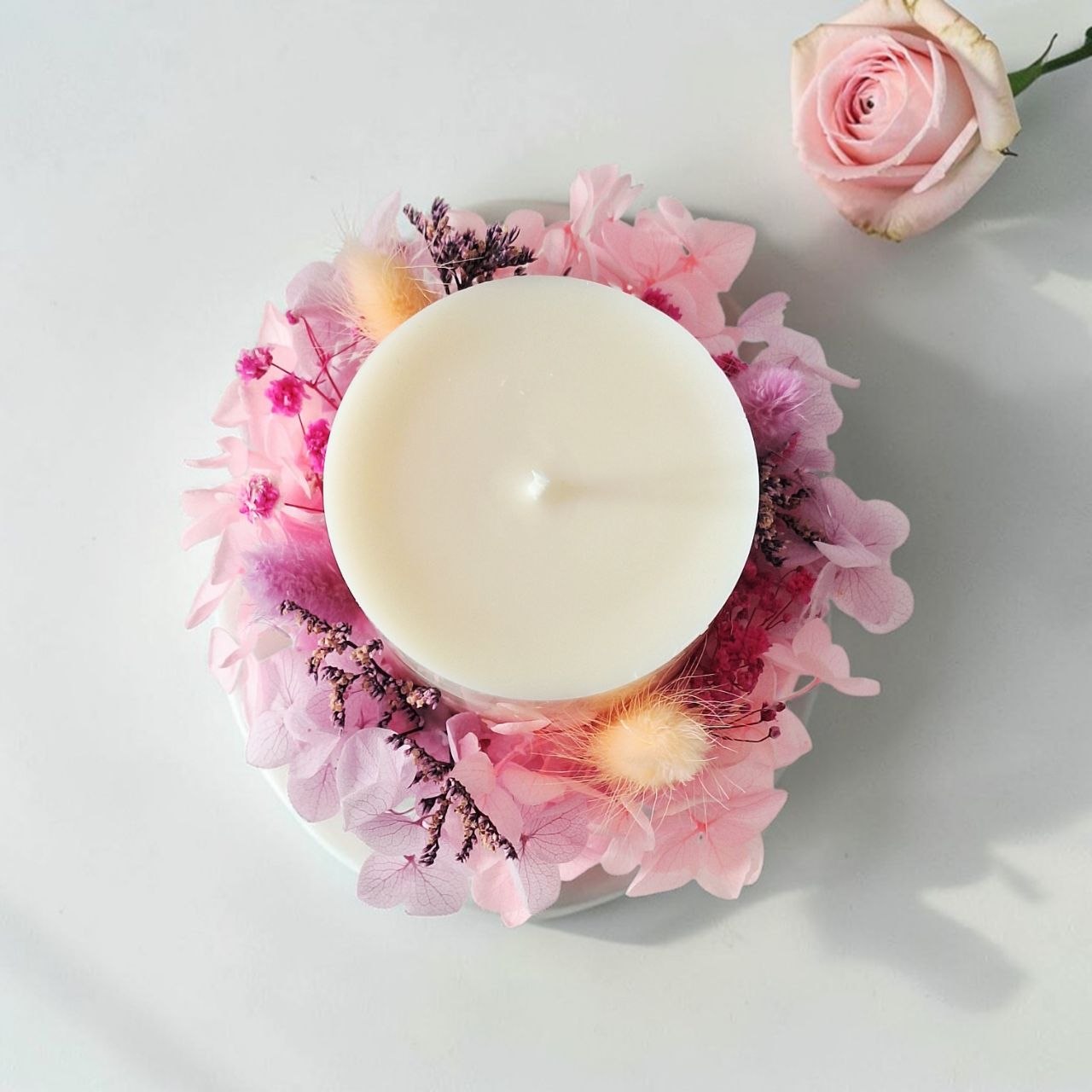 Top view of soft rose botanical candle with preserved flowers arranged around the candle