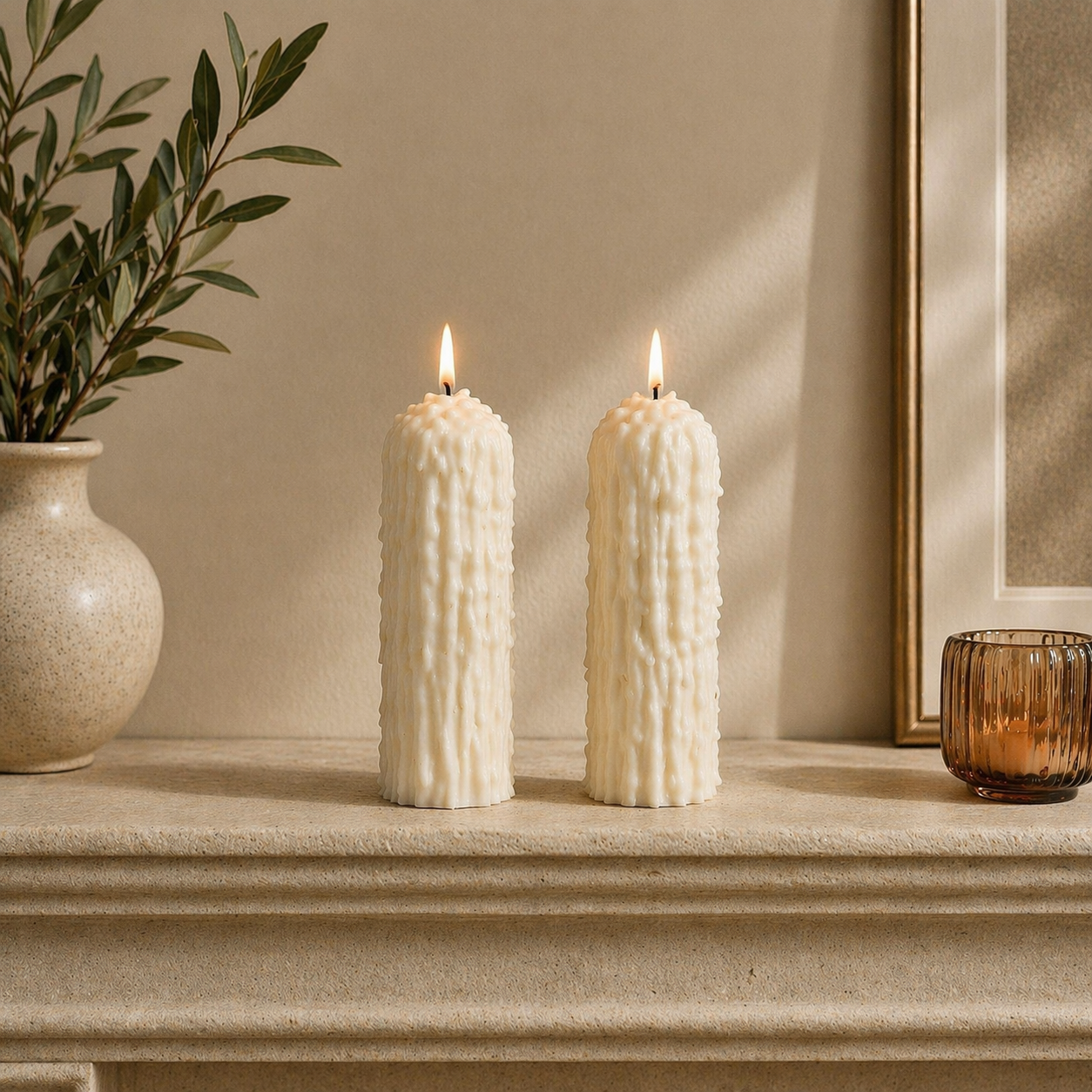 Lit white drip effect soy wax pillar candles styled on a mantel for minimalist home decor